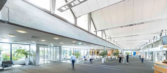 Modern airport terminal interior featuring spacious seating areas, large windows, and a clean, minimalist design.