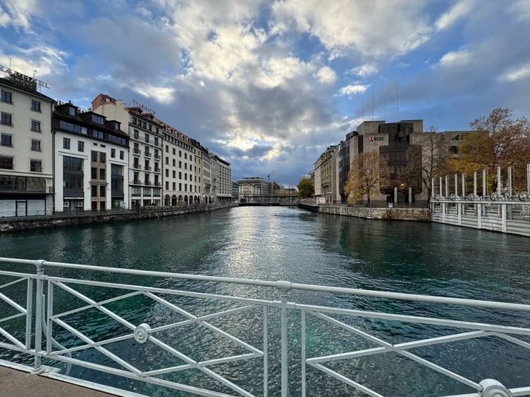 Blick auf einen Fluss, der von Gebäuden gesäumt ist, mit einem bewölkten Himmel darüber. Die Szene fängt die architektonischen Details am Ufer ein.