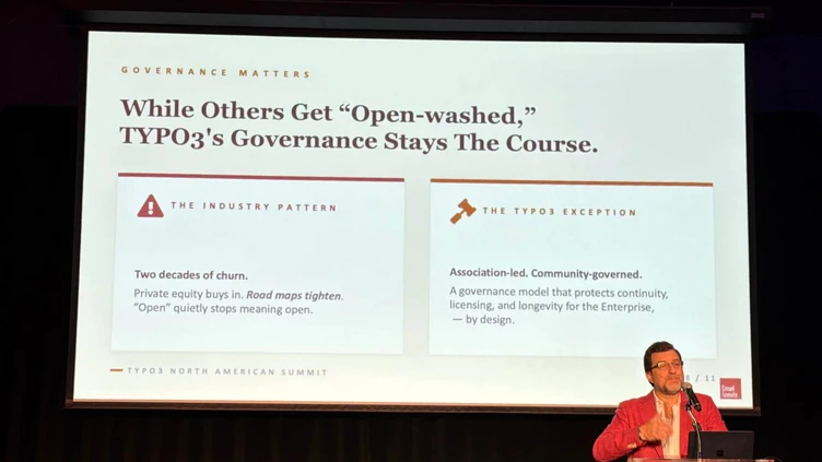 Ein Redner in einem roten Blazer präsentiert beim TYPO3 North America Summit und spricht über Governance und Community-Engagement. Der Text auf dem Bildschirm hebt wichtige Punkte zu Branchentrends und der Governance von TYPO3 hervor.