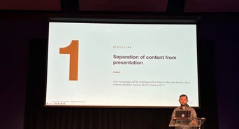 A speaker presents on stage, discussing the separation of content from presentation, with a slide displaying the number "1" and key points.