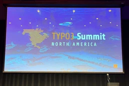 Präsentationsbildschirm, der 'TYPO3 Summit Nordamerika' mit einem blauen aquatischen Hintergrund und einem Podium davor anzeigt.