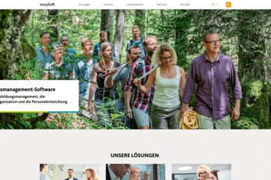 A group of diverse individuals is walking together on a forest trail, engaged in conversation. They appear to be participating in an outdoor activity or team-building event.