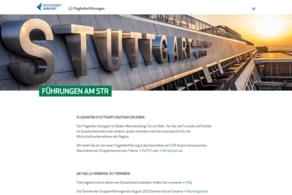 Der Flughafen Stuttgart ist mit einem auffälligen Schild am Terminalgebäude versehen, das ein modernes architektonisches Design aufweist. Der Text hebt die geführten Touren hervor, die am Flughafen angeboten werden, und lädt die Besucher ein, die Geschichte und die Einrichtungen des Flughafens zu erkunden.