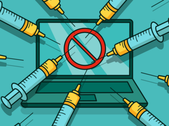 A laptop is surrounded by multiple syringes, with a red prohibition symbol displayed on the screen, indicating a message against vaccination or medical intervention.